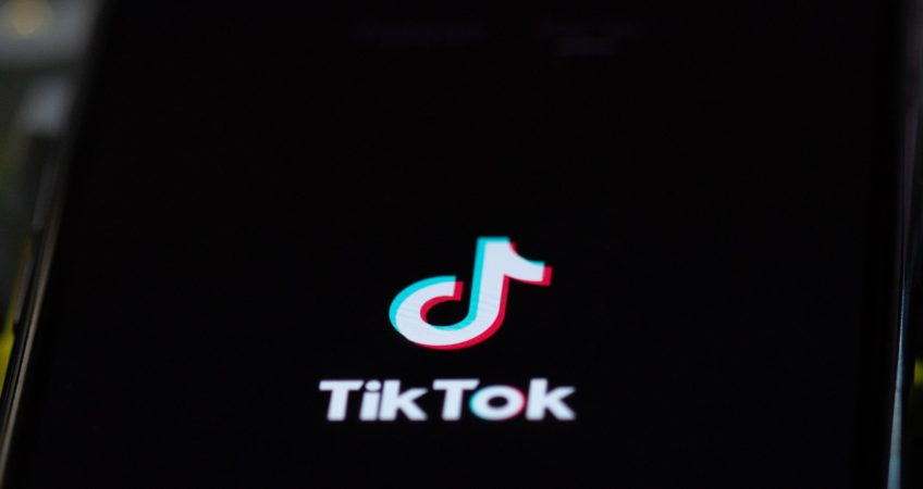 Black phone screen with 'Tik Tok' on the screen in white letters and the 'Tik Tok' logo